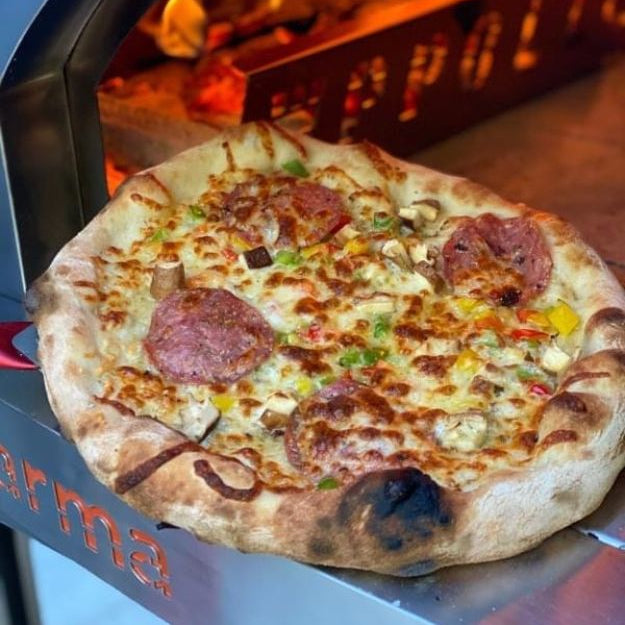 Pizza being cooked in a wood-fired oven with 'Wppco' branding.