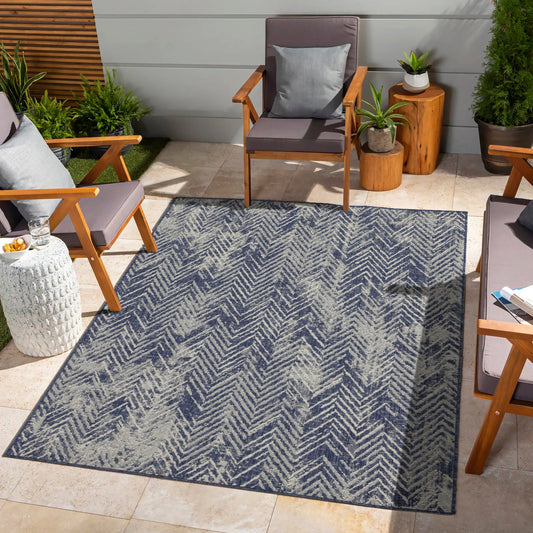 Outdoor patio with a blue patterned rug, wooden chairs, and potted plants.