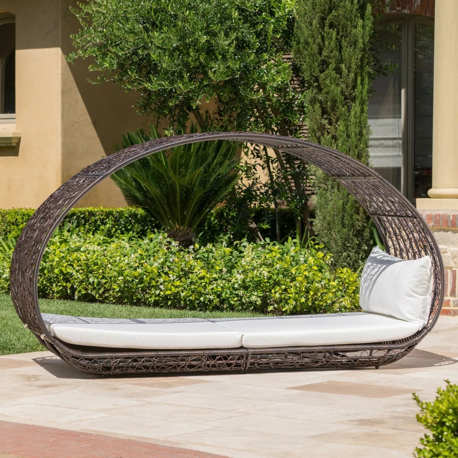 Round wicker outdoor chair with white cushions on a patio