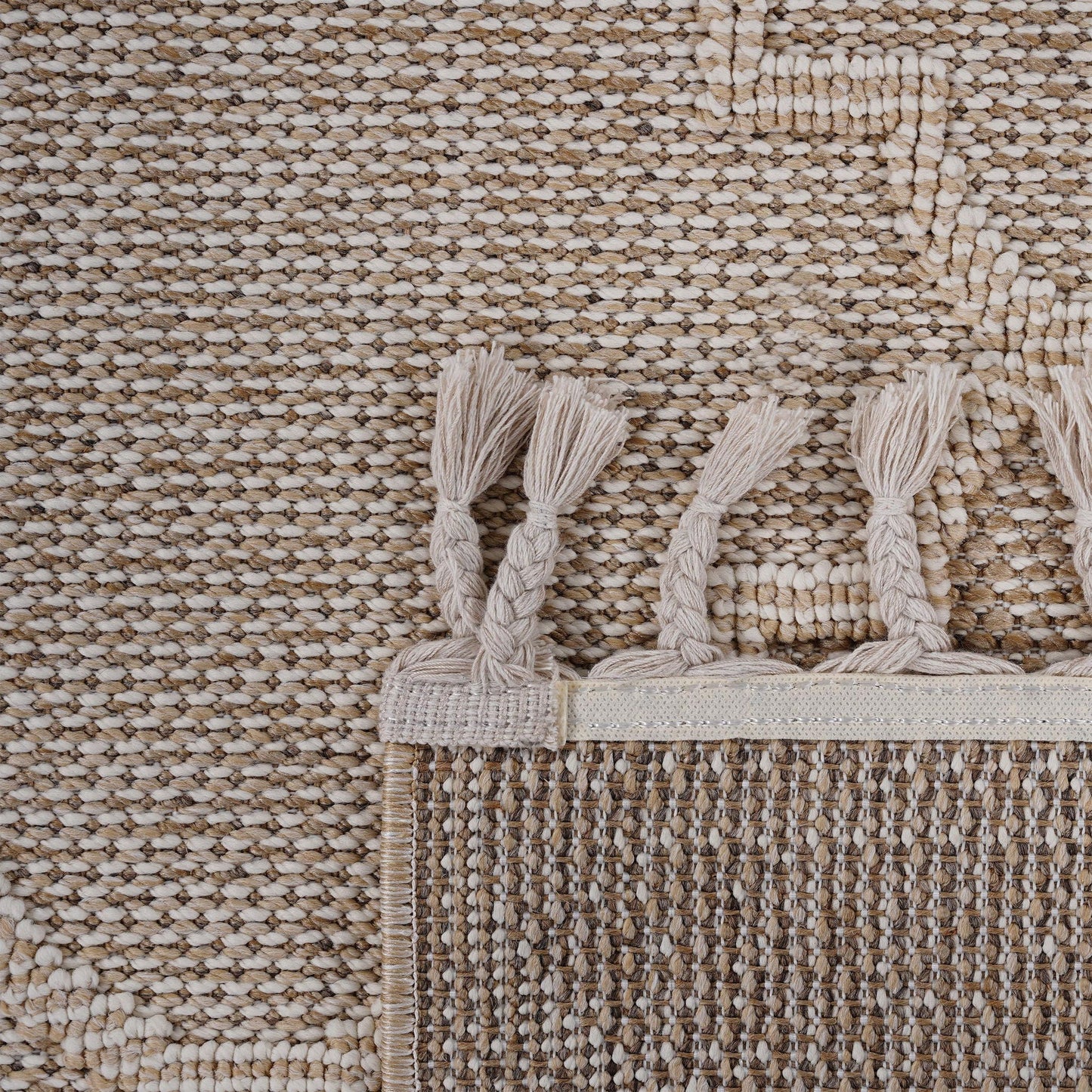 Close-up of a textured beige rug with tassels