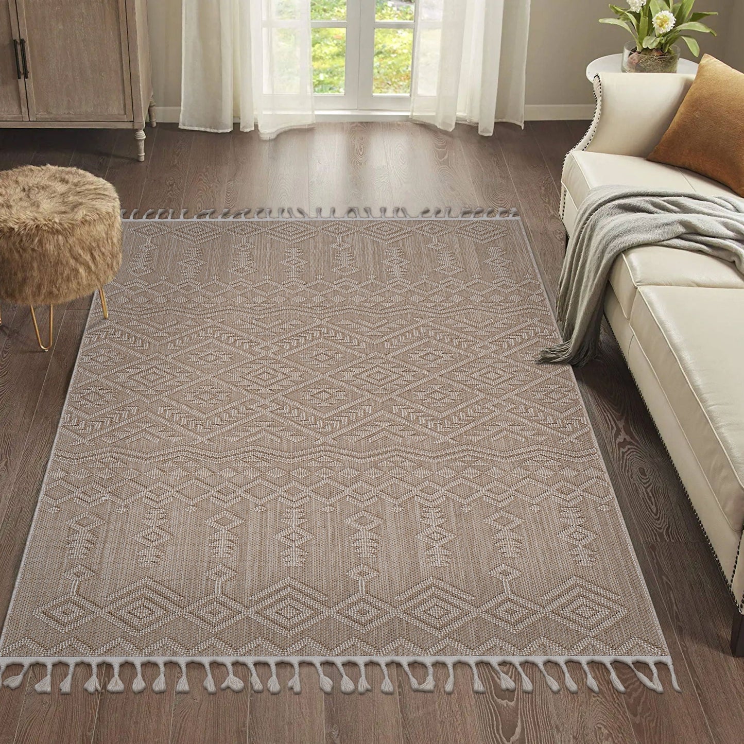 Patterned beige rug on a wooden floor with a sofa and ottoman in a living room.