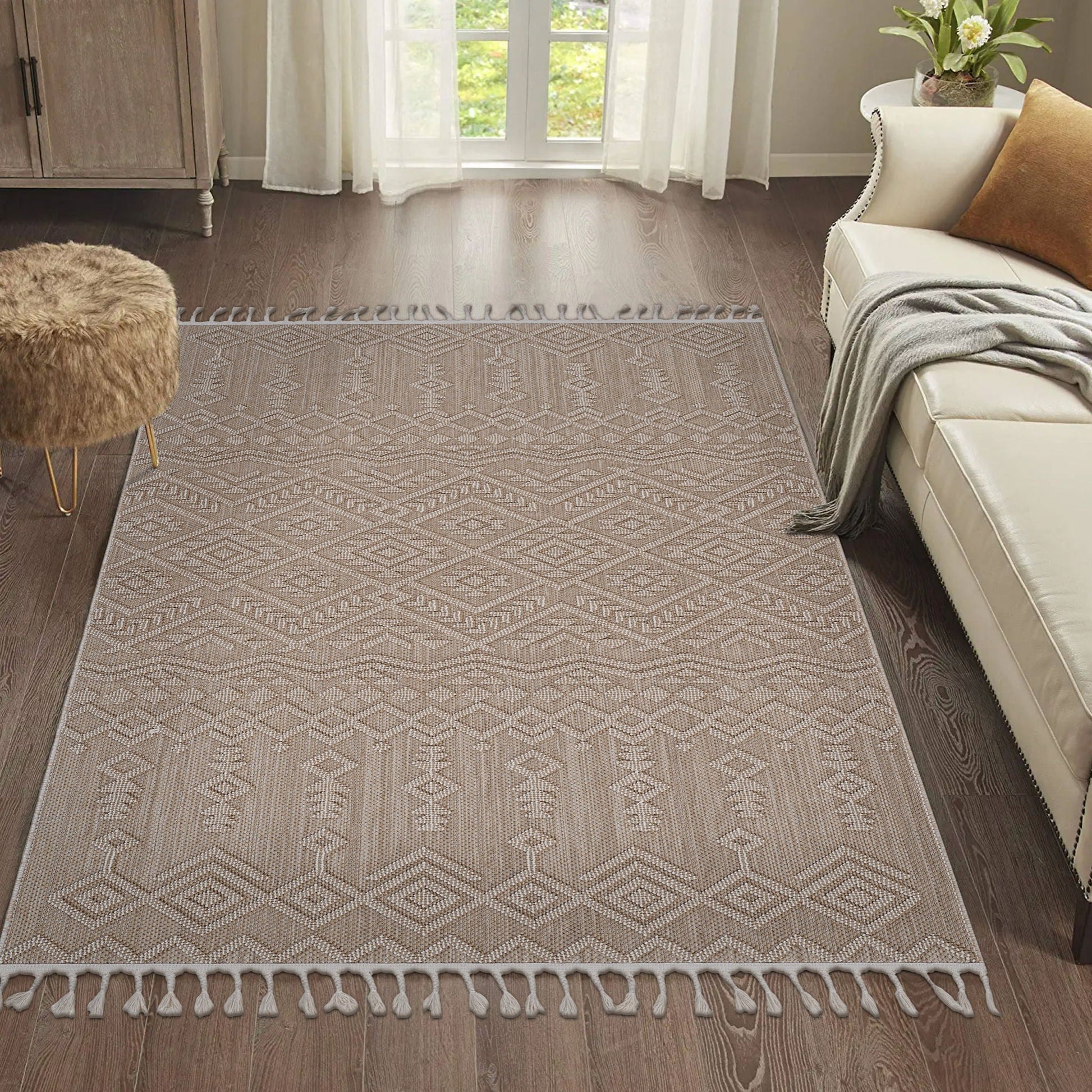 Patterned beige rug on a wooden floor with a sofa and ottoman in a living room.