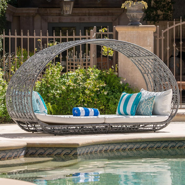 Wicker daybed with cushions by a poolside
