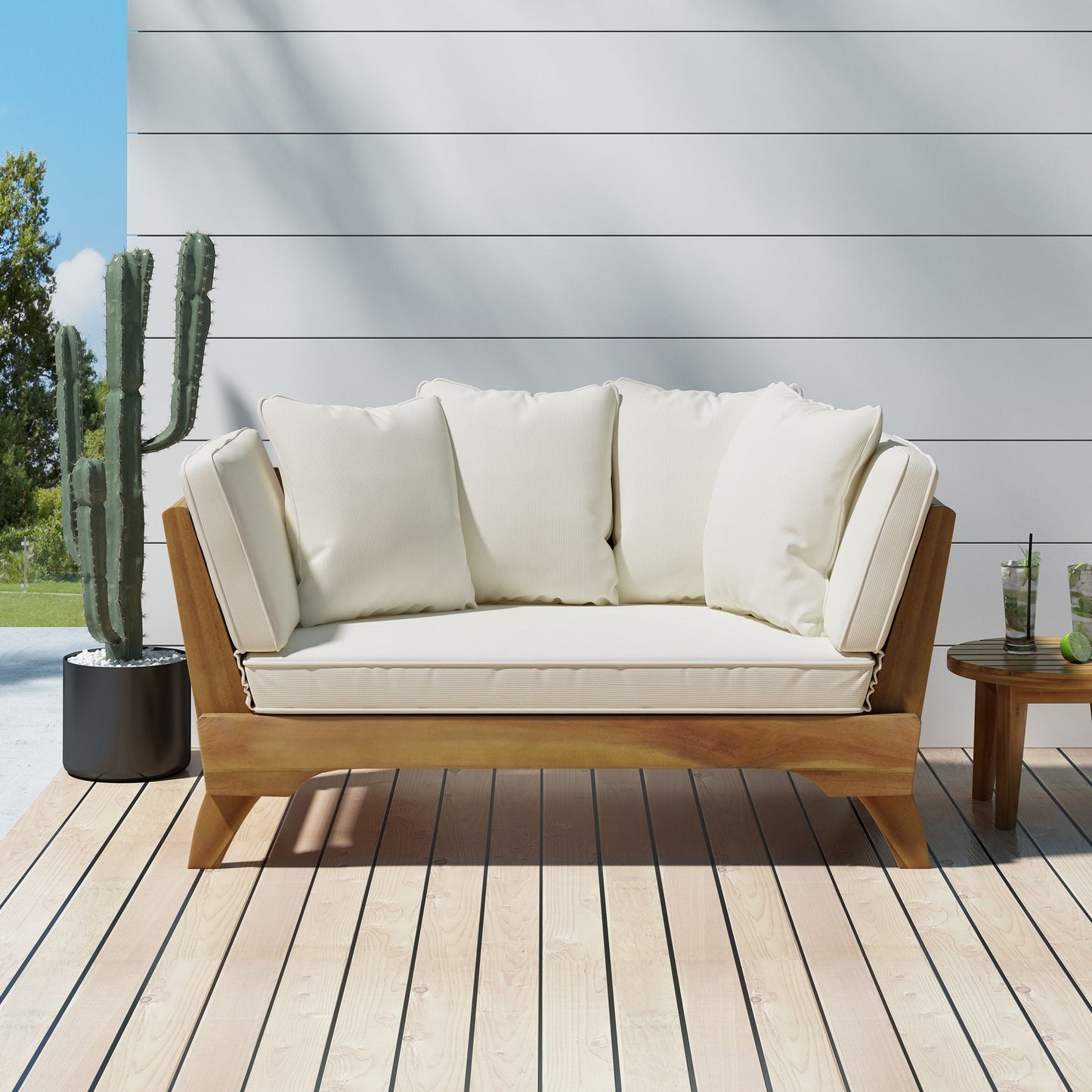 Wooden outdoor sofa with white cushions on a wooden deck, with a cactus plant in the background.