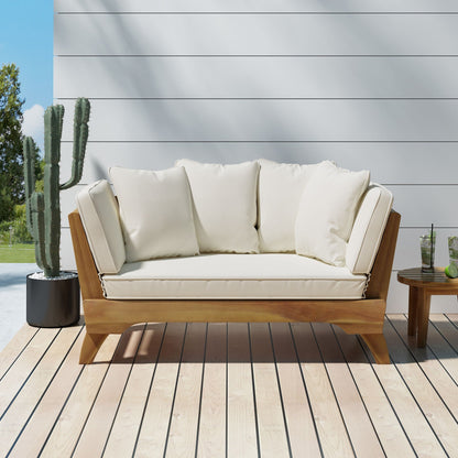 Wooden outdoor sofa with white cushions on a wooden deck, with a cactus plant in the background.