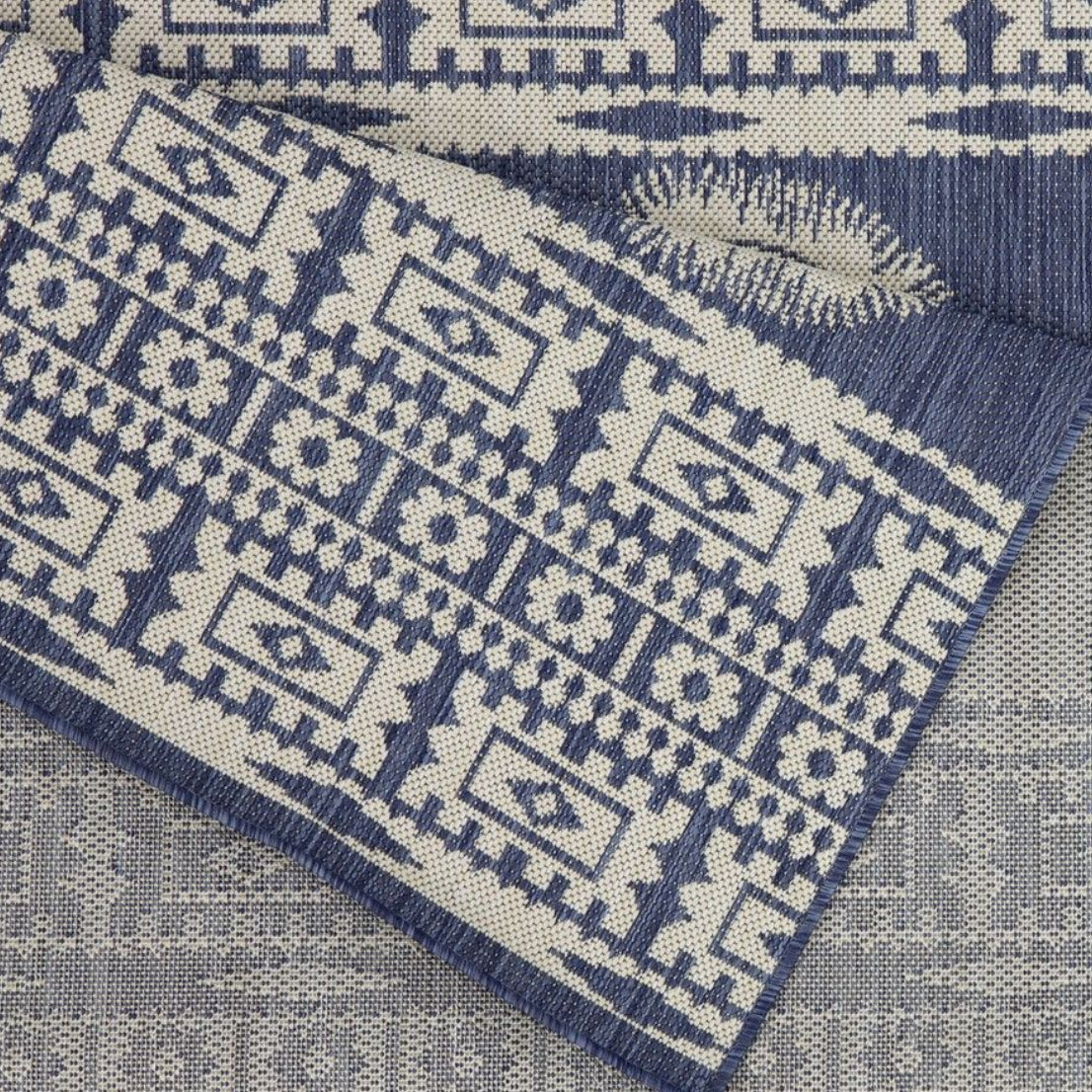 Blue and beige patterned rug corner on a neutral background