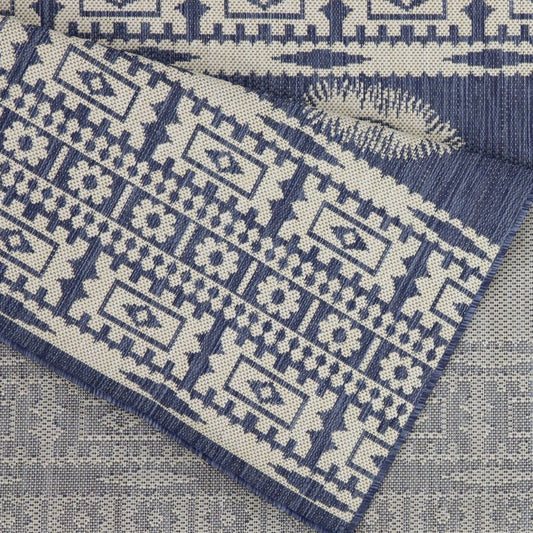 Blue and beige patterned rug corner on a neutral background