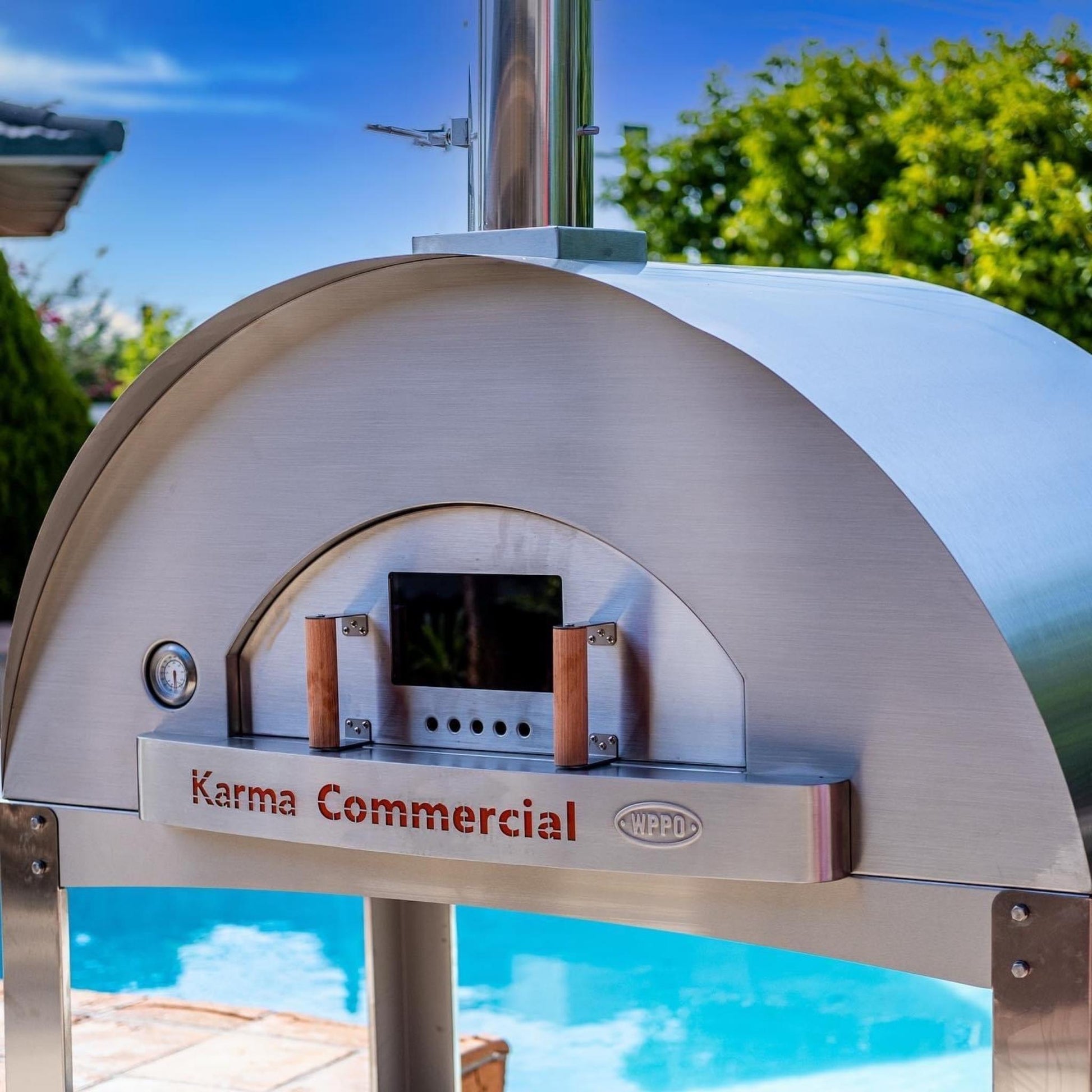 Karma Commercial pizza oven outdoors with pool and trees in the background