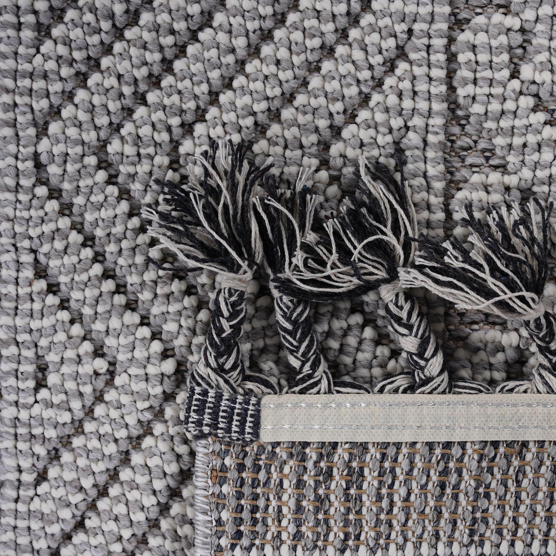 Close-up of a textured gray rug with tassels