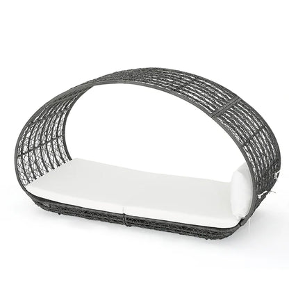 Black wicker pet bed with a white cushion on a white background