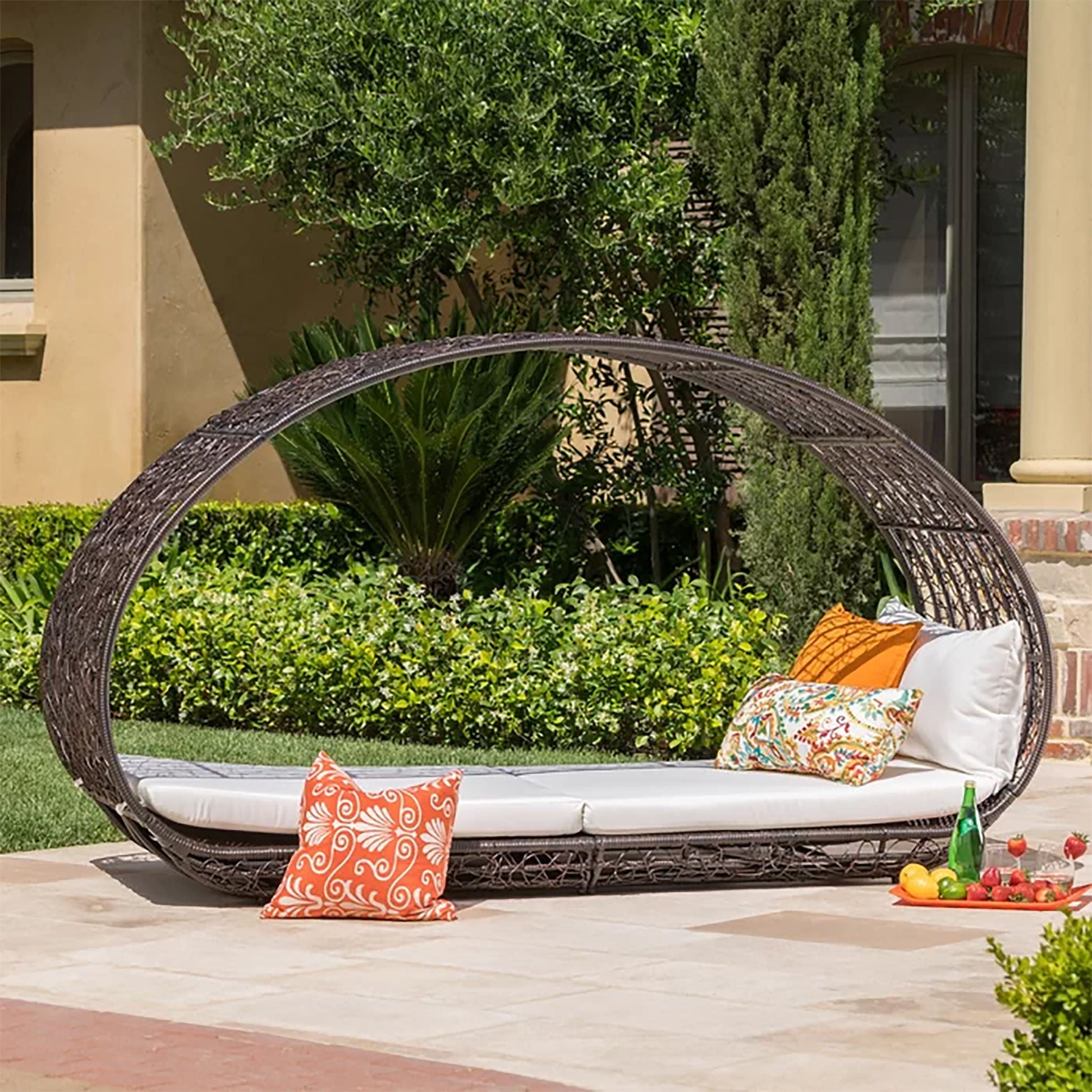 Wicker outdoor swing with cushions and a small table on a patio