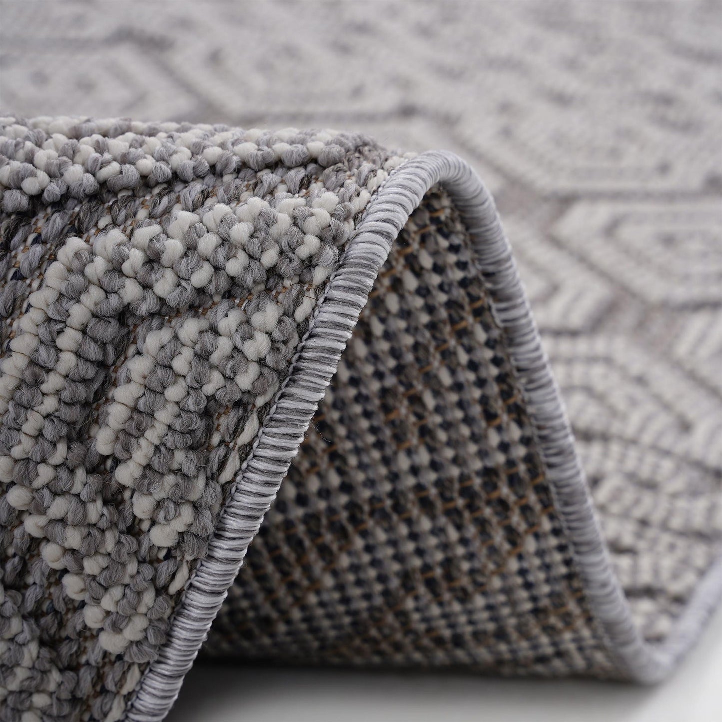 Close-up of a textured gray rug with a geometric pattern.