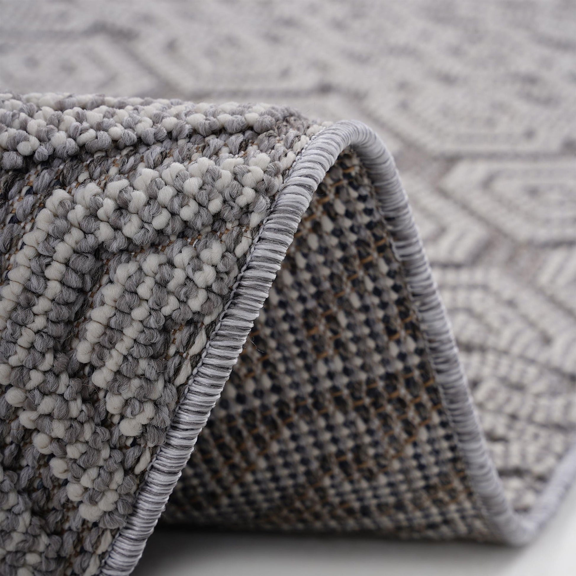 Close-up of a textured gray rug with a geometric pattern.