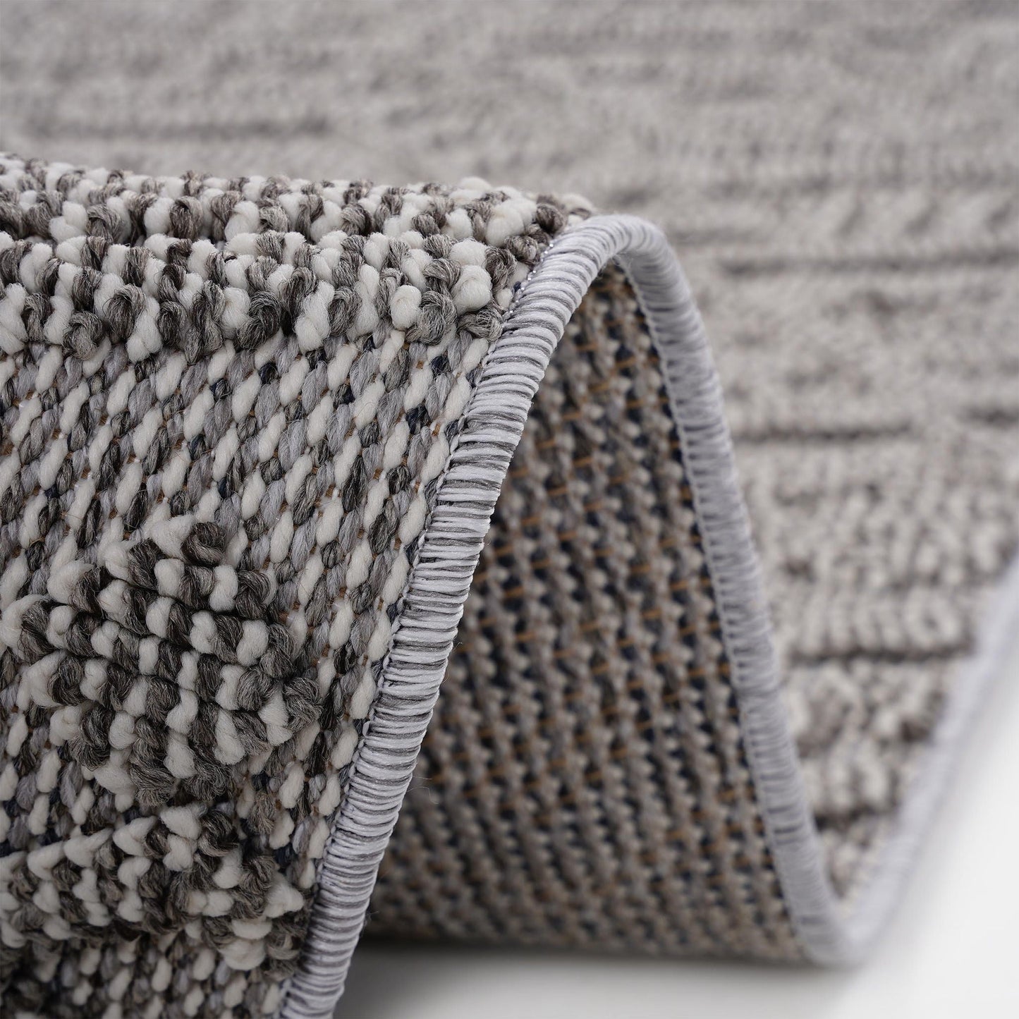 Close-up of a textured rug with a geometric pattern on a neutral background