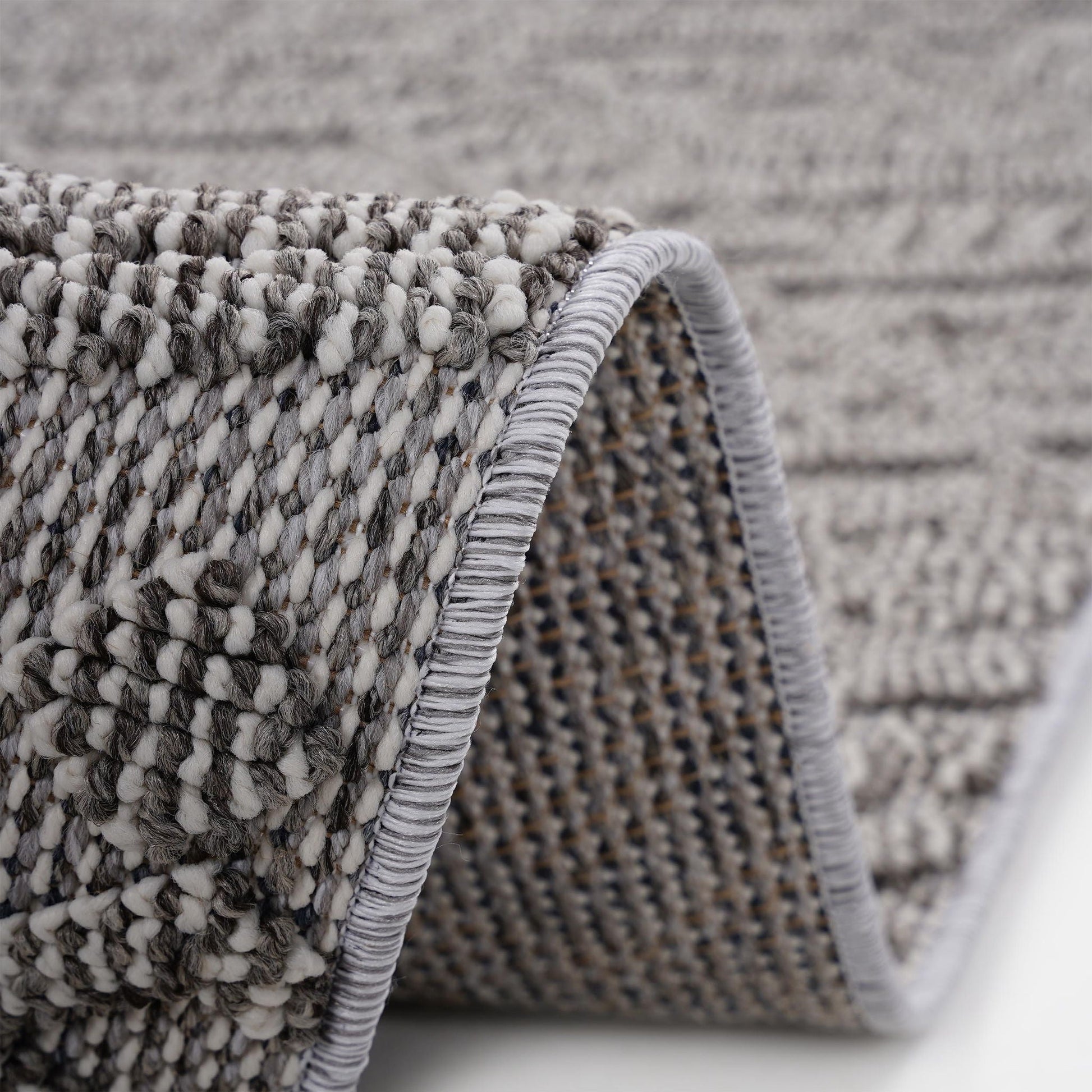 Close-up of a textured rug with a geometric pattern on a neutral background