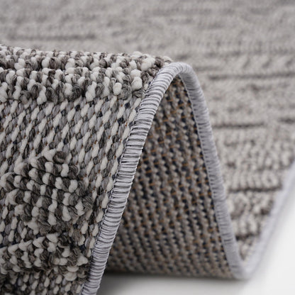Close-up of a textured rug with a geometric pattern on a neutral background