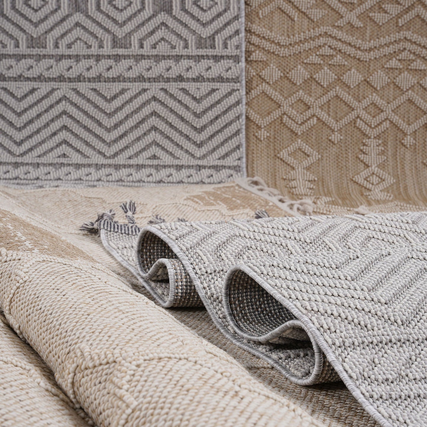 Rolls of patterned rugs in various colors on a neutral background