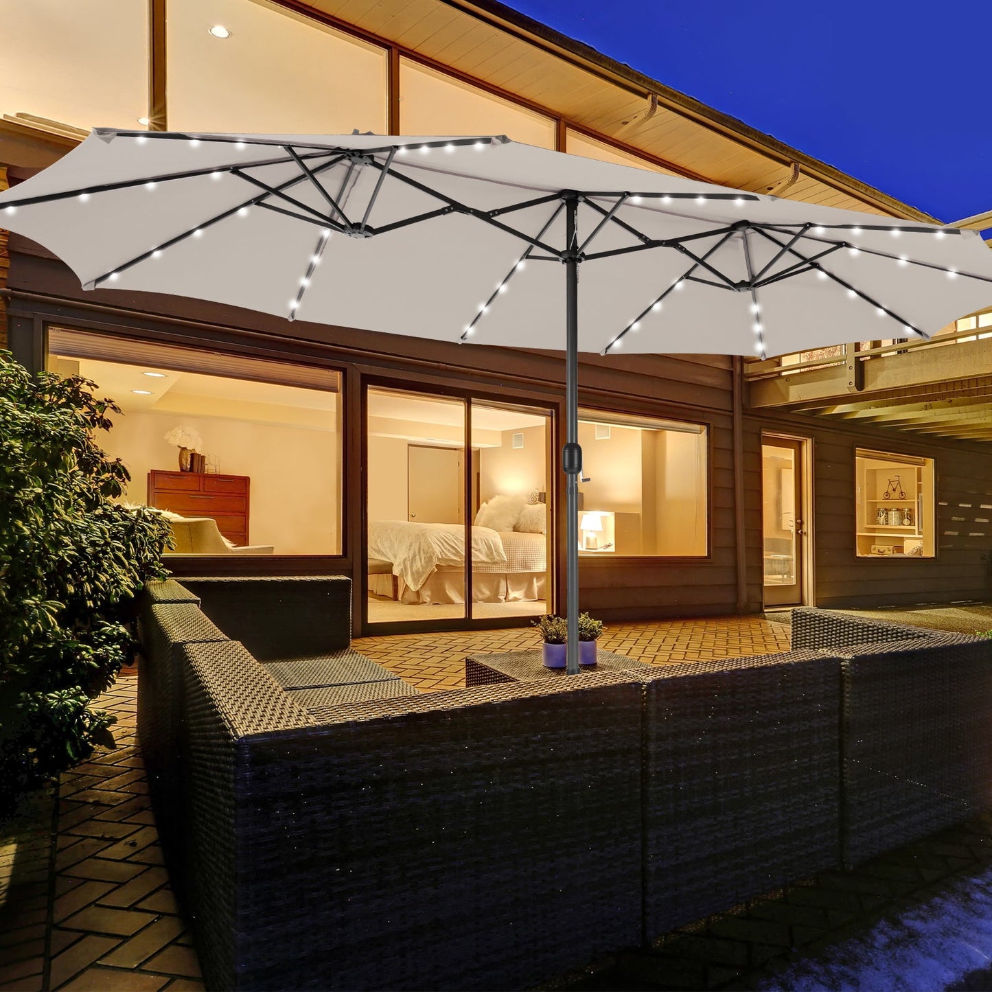 Large patio umbrella with LED lights over a outdoor seating area at night.