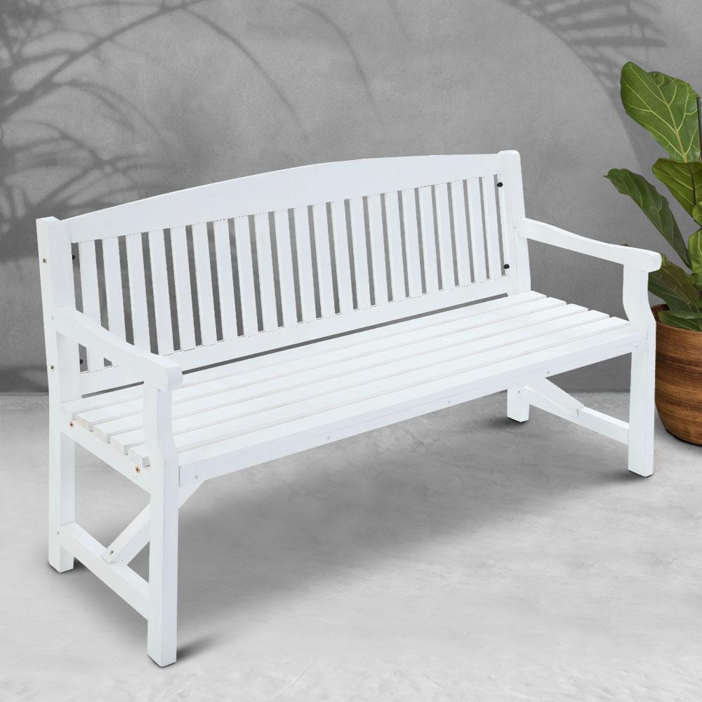White wooden bench on a light gray floor with a plant in the background