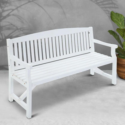 White wooden bench on a light gray floor with a plant in the background