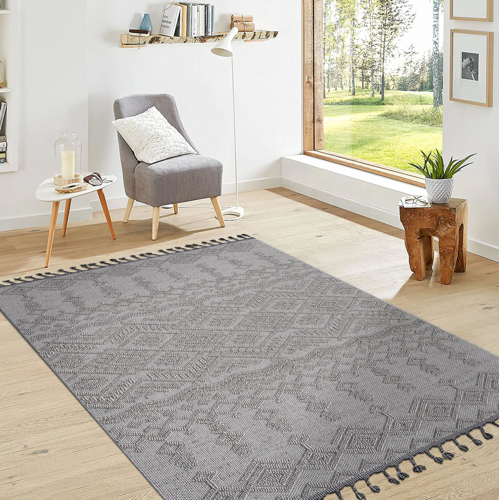 Living room with a gray patterned rug, gray armchair, and a large window.