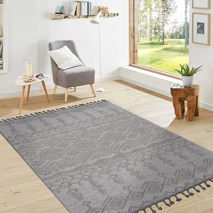 Living room with a gray patterned rug, gray armchair, and a large window.