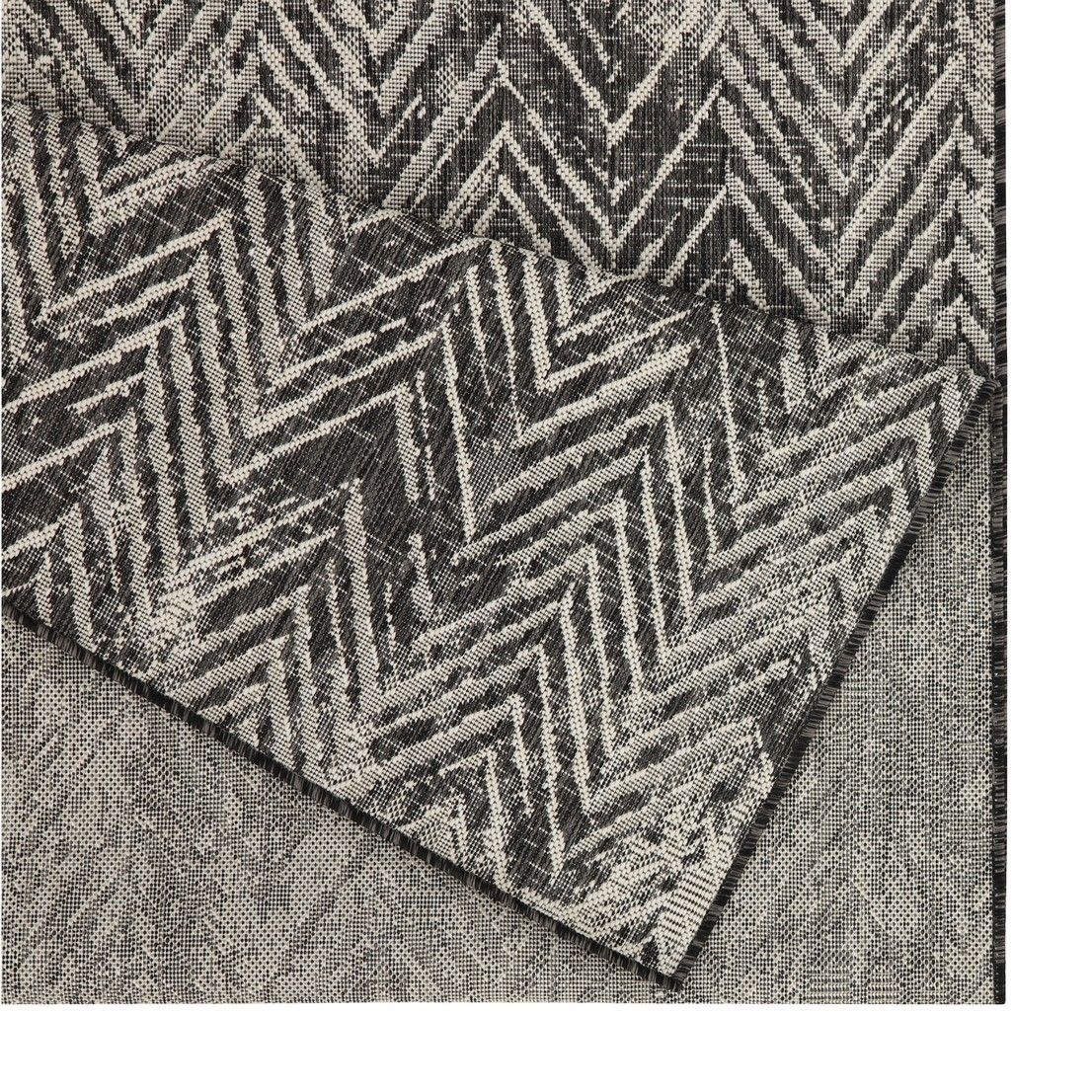 Textured rug with a geometric pattern on a plain background