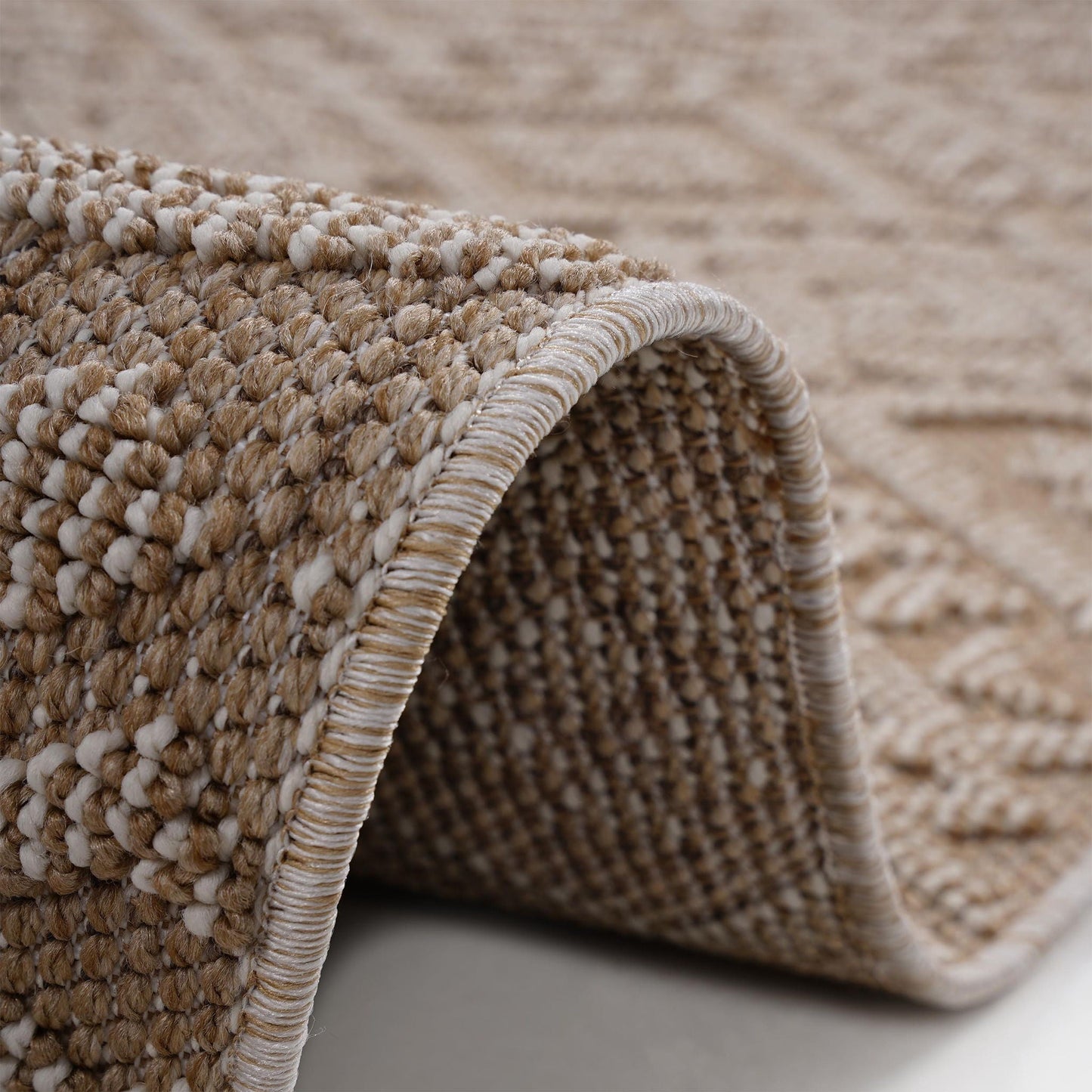 Close-up of a textured beige and brown rug corner.