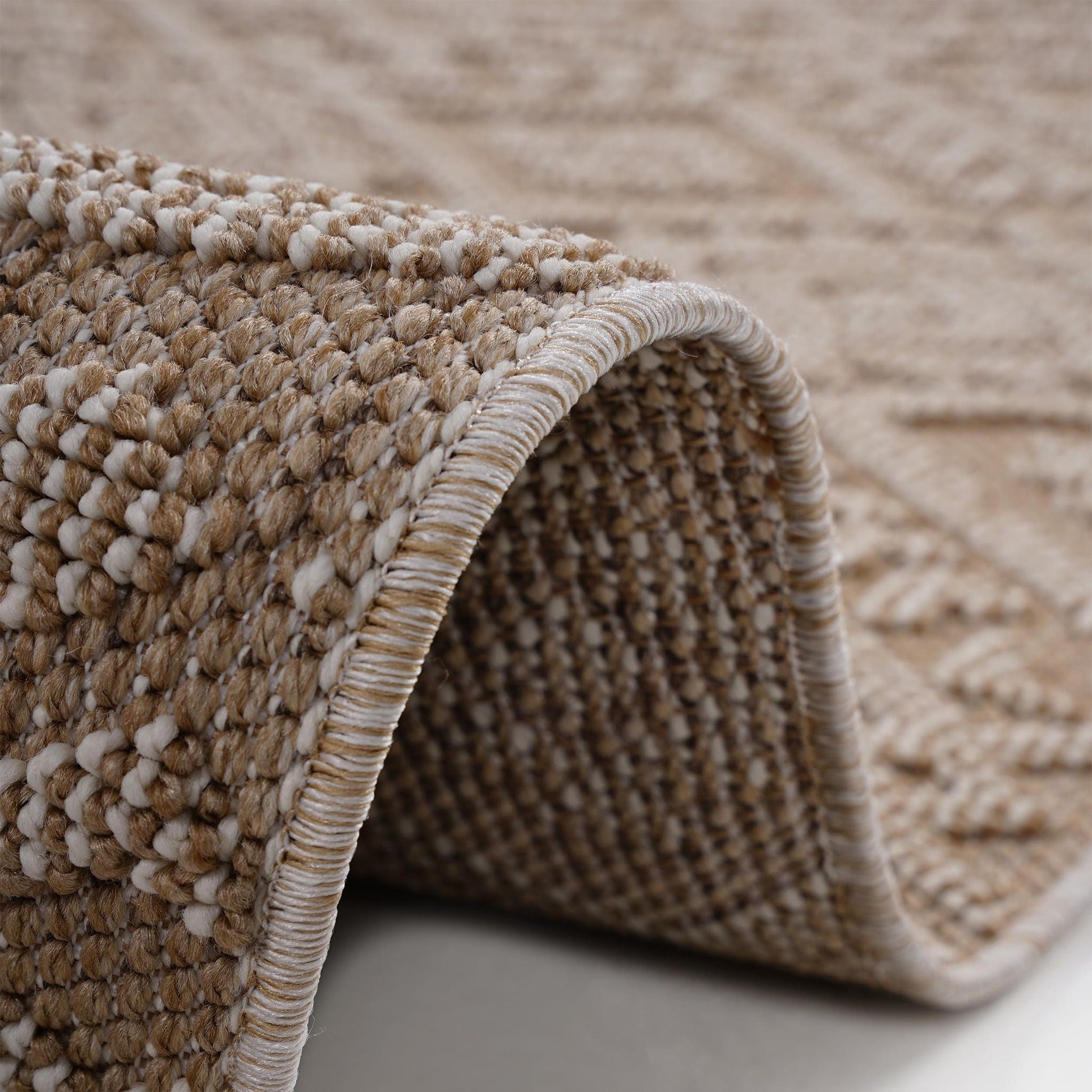 Close-up of a textured beige and brown rug corner.