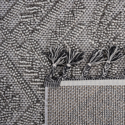 Close-up of a textured gray rug with tassels at the corner.