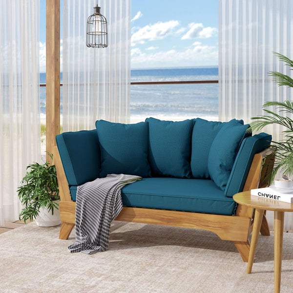 Blue outdoor sofa with wooden frame in a room with large windows showing a view of the ocean.