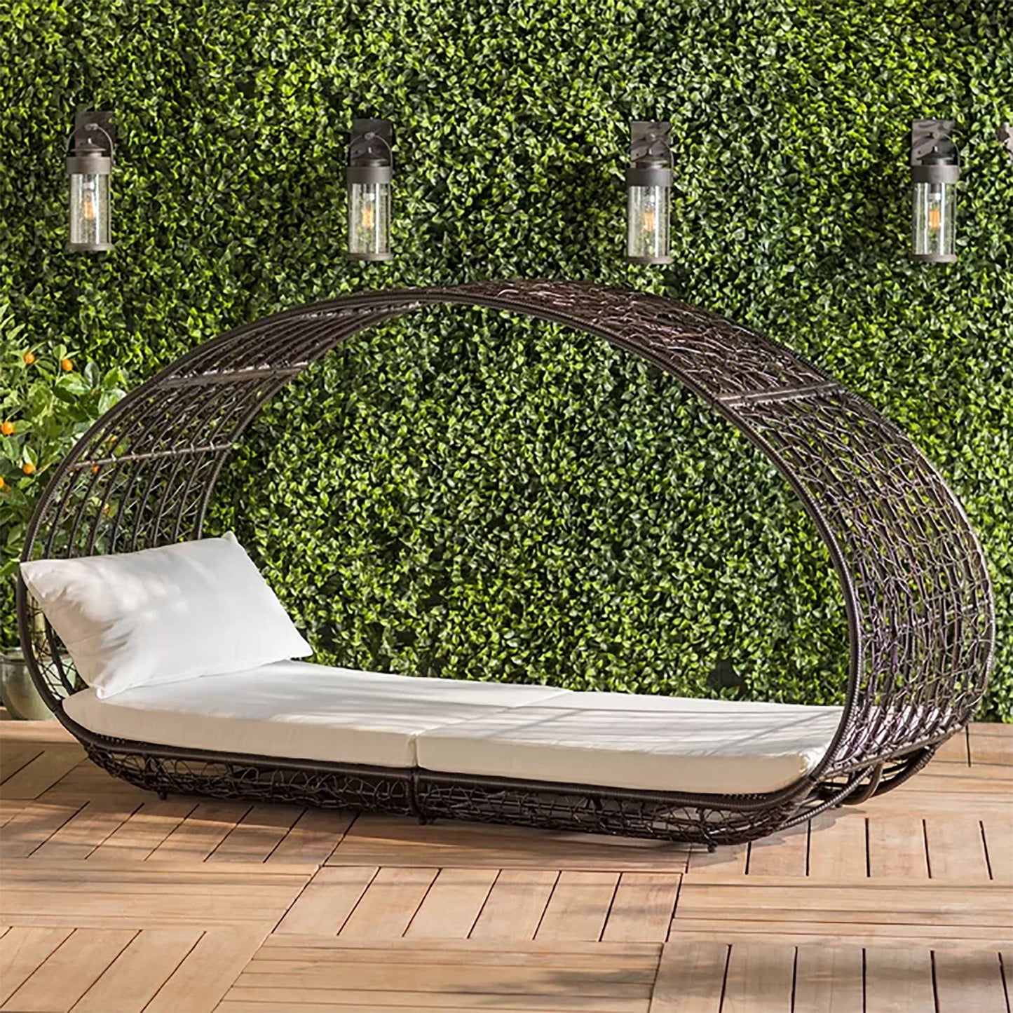 Wicker daybed with white cushion against a green wall