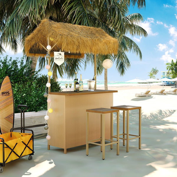 Beachside bar setup with straw roof, bottles, and surfboard on a sunny day.