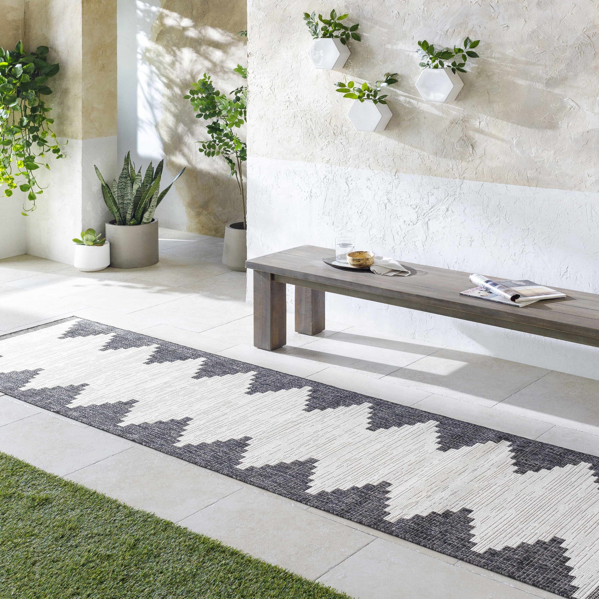 Patterned rug on a patio with a bench and plants