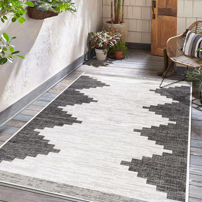 Geometric patterned rug on a wooden floor with plants and a chair in the background