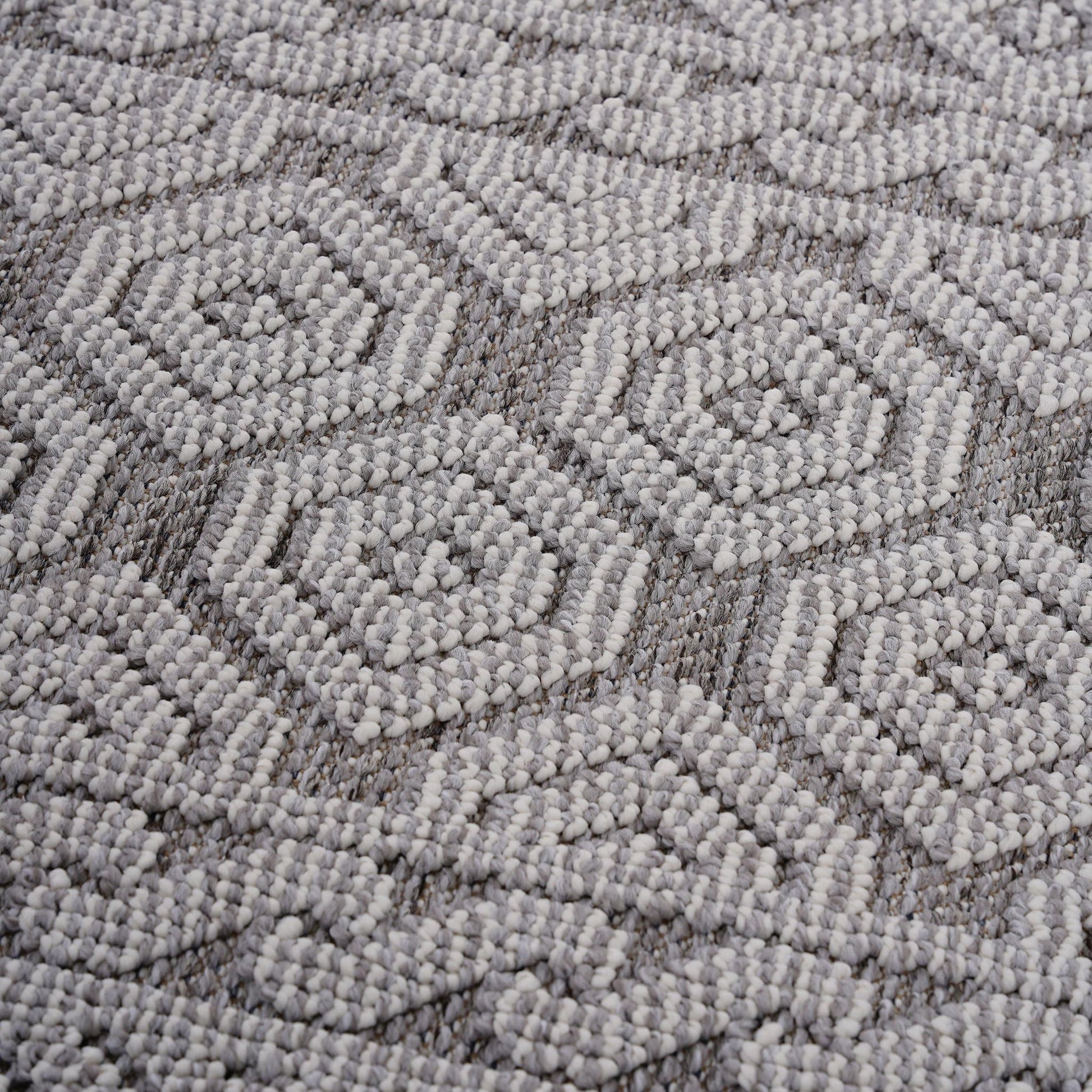 Close-up of a textured gray carpet with a geometric pattern