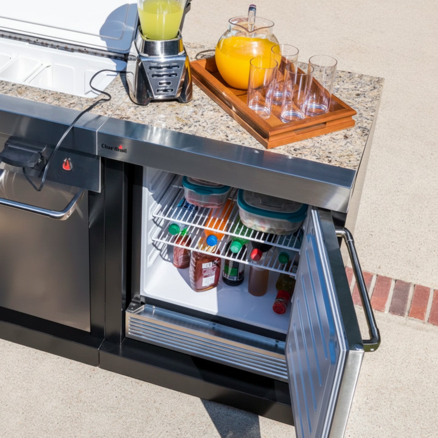 Outdoor kitchen counter with a refrigerator, drinks, and a blender.